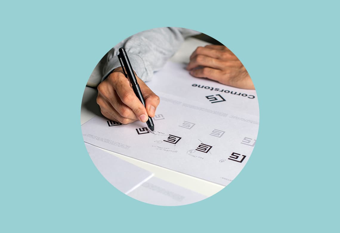 Asian graphic designer making notes on logo designs, using computers, designing logos, and showcasing the corporate identity and logo design process for blog titled "timeless logo design"